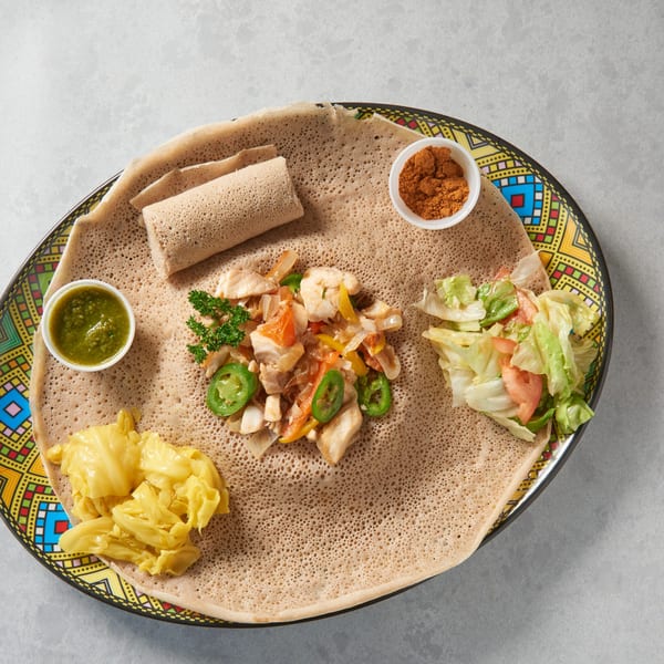 Ethiopian injera bread with chicken tibs, cabbage, salad, green sauce, and berbere spice.