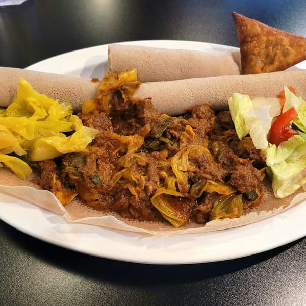 Altu's Ethiopian Cuisine platter with injera, meat stew, yellow cabbage, salad, and a samosa.