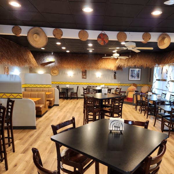 Interior of Altu's Ethiopian Cuisine with straw decor, booths, and dark tables with wooden chairs.