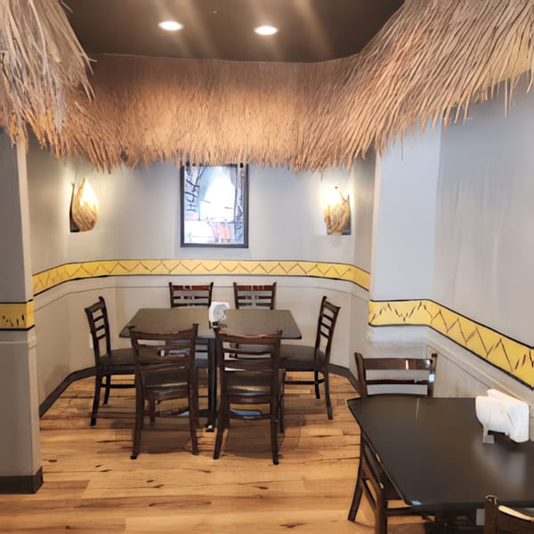 Altu's Ethiopian Cuisine dining area with thatched ceiling accents, wooden tables, and yellow patterned walls.