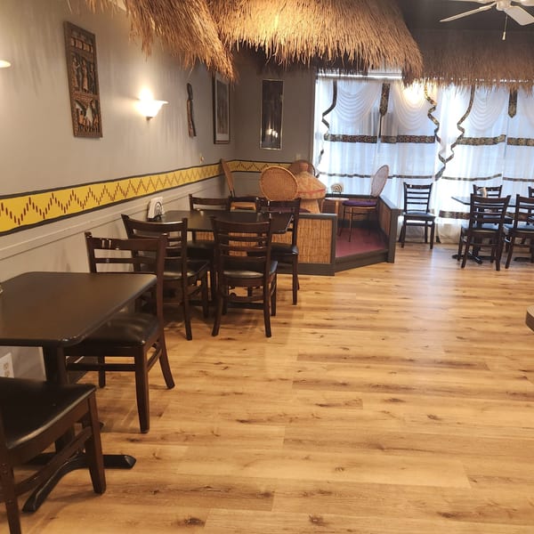 Interior of Altu's Ethiopian Cuisine with thatched ceilings, wooden tables, chairs, and cultural wall decor.