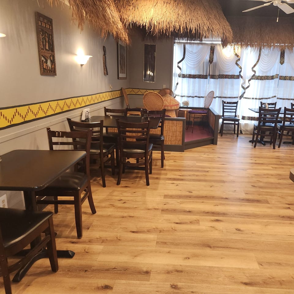 Interior of Altu's Ethiopian Cuisine with thatched ceilings, wooden tables, chairs, and cultural wall decor.