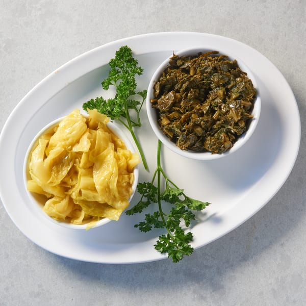 Two white bowls of Ethiopian gomen and tikil gomen, garnished with parsley on a white platter.